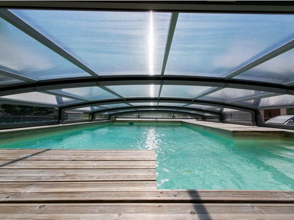 Intérieur d'un abri de piscine bas au-dessus d'un bassin et d'une terrasse en bois
