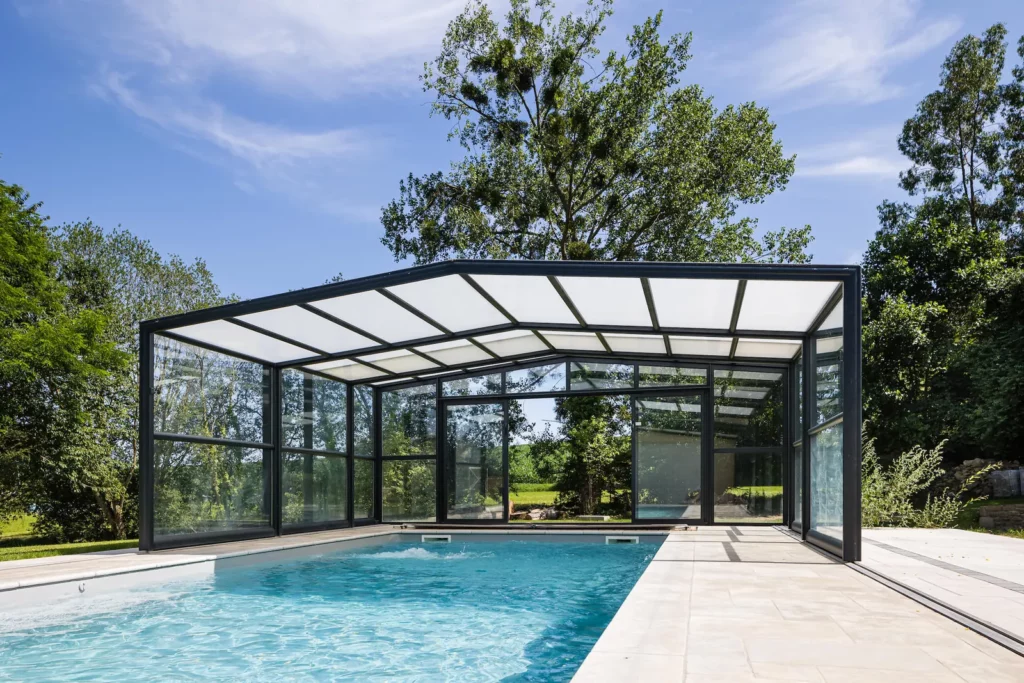 Abri de piscine haut vitré installé dans un jardin
