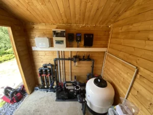 Cabane technique en bois abritant la filtration et le matériel d'entretien
