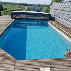 Piscine avec abri haut et terrasse en bois face à la campagne, Vosges