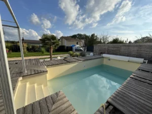 Piscine couverte par un abri télescopique bas avec plage en bois, Vosges