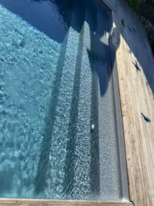 Escalier immergé d'une piscine avec plage en bois et eau limpide, Vosges