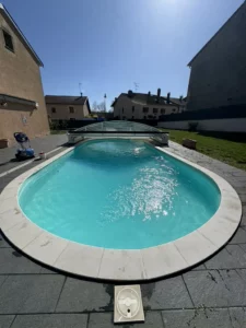 Piscine de forme libre bordée d'une plage en bois en milieu urbain, Vosges