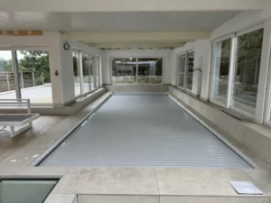 Piscine intérieure équipée d'un volet immergé devant de grandes baies vitrées, Vosges