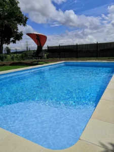 Piscine à angles arrondis avec liner bleu dans un jardin clos, Vosges