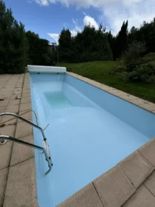 Piscine à liner bleu clair avec échelle inox posée sur une pelouse, Vosges