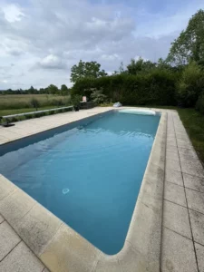 Piscine rectangulaire avec plage en pierre claire dans un grand jardin, Vosges