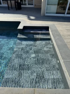 Piscine rénovée avec escalier immergé et margelles en pierre grise, Vosges