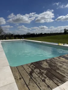 Piscine bordée d'une terrasse en bois patiné en pleine campagne, Vosges