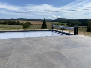 Piscine à volet fermé bordée d'une terrasse en béton lissé, Vosges