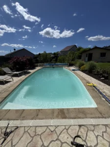 Piscine avec volet roulant et terrasse en pierre devant une maison, Vosges