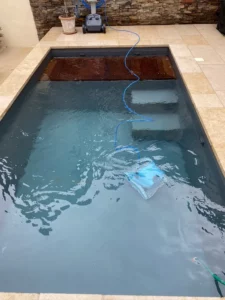 Piscine rénovée en PVC armé gris avec robot nettoyeur en fonctionnement, Vosges
