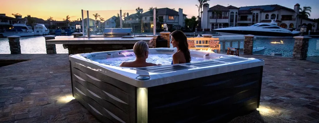 Deux personnes dans un spa extérieur face à un coucher de soleil