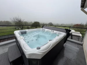 Spa extérieur quatre places installé sur une terrasse avec vue sur la campagne vosgienne