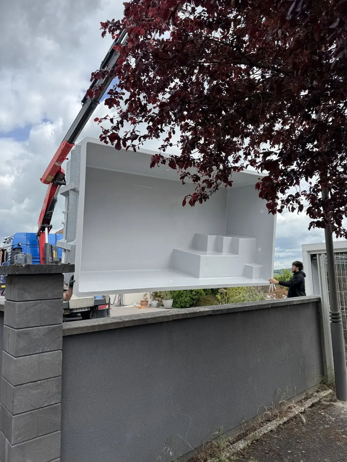 Grue en cours d'installation d'une coque de piscine polyester sur un chantier à Poussay