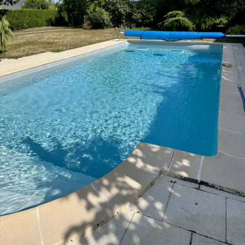 Piscine avec liner gris clair rénové et terrasse en pierre, réalisation Reflets d'Eau à Charmes