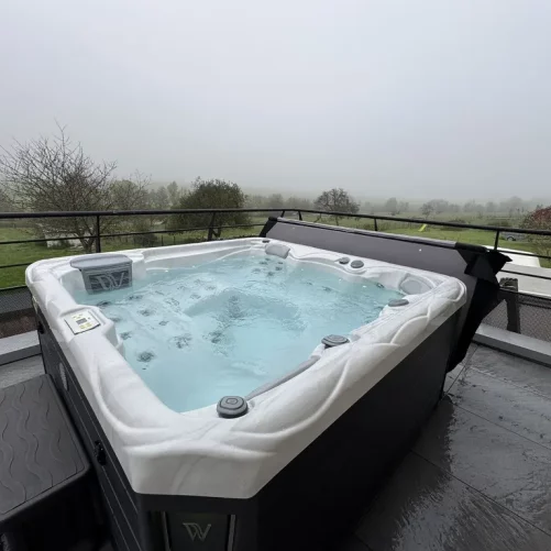 Spa extérieur quatre places installé sur une terrasse avec vue sur la campagne vosgienne